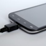 Caricabatterie del telefono collegato a una presa di corrente, con un bollettino elettrico in evidenza.