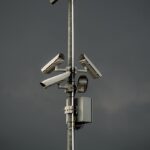 Telecamera di sicurezza solare installata all'esterno, con pannello solare visibile e sfondo verde.