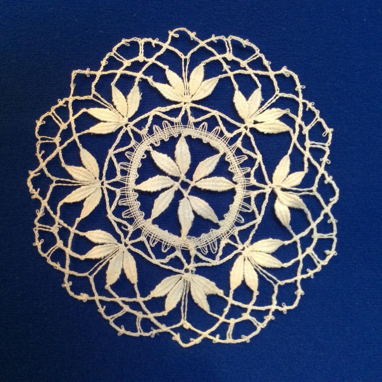 Vecchi centrini della nonna esposti su un tavolo, simbolo di tradizione e valore artigianale.