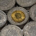 Moneta rara battuta all'asta per oltre 30mila euro, esposta su un tavolo con luci soffuse.